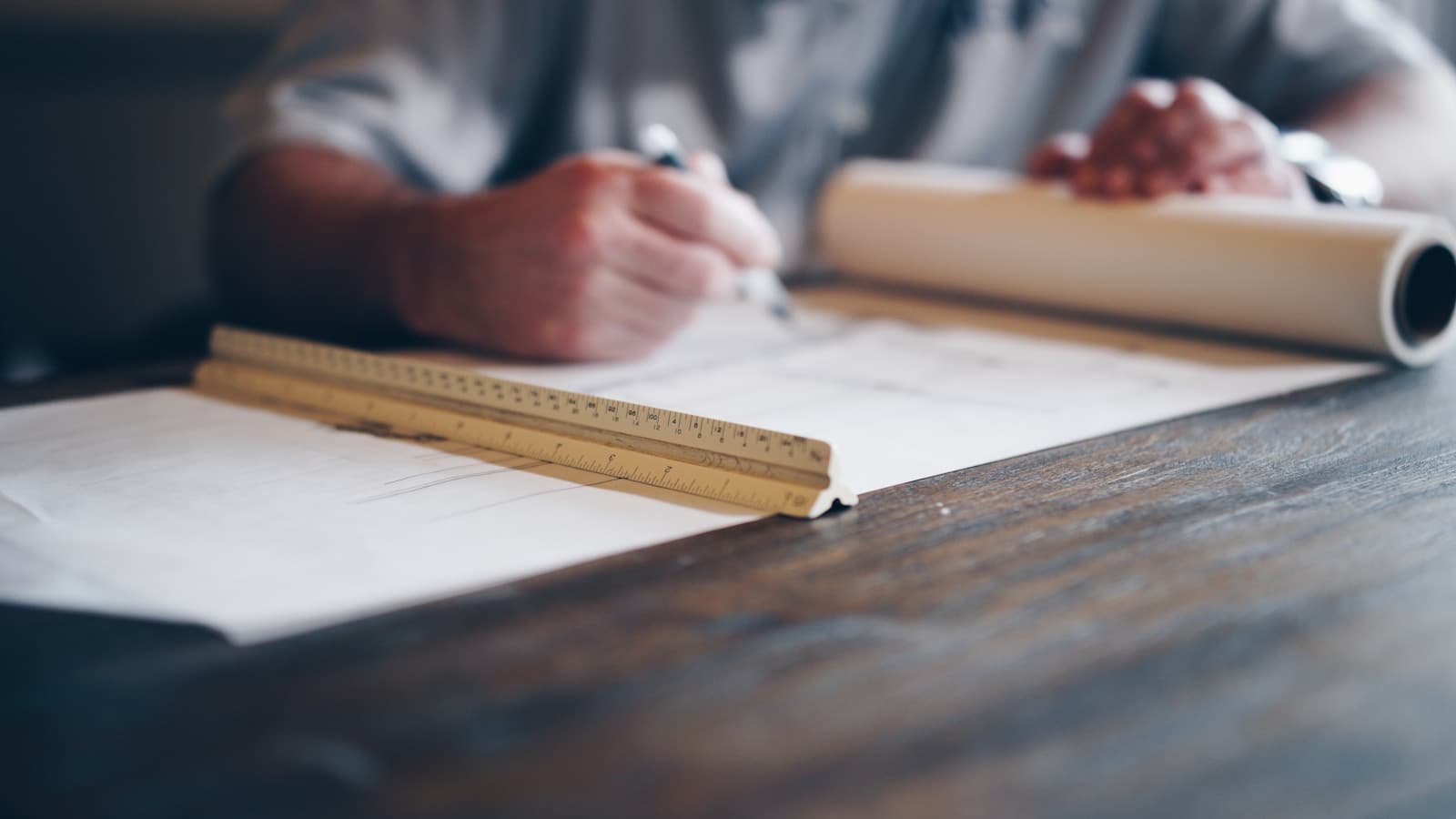 Hands drafting renovation plans on a blueprint at a desk