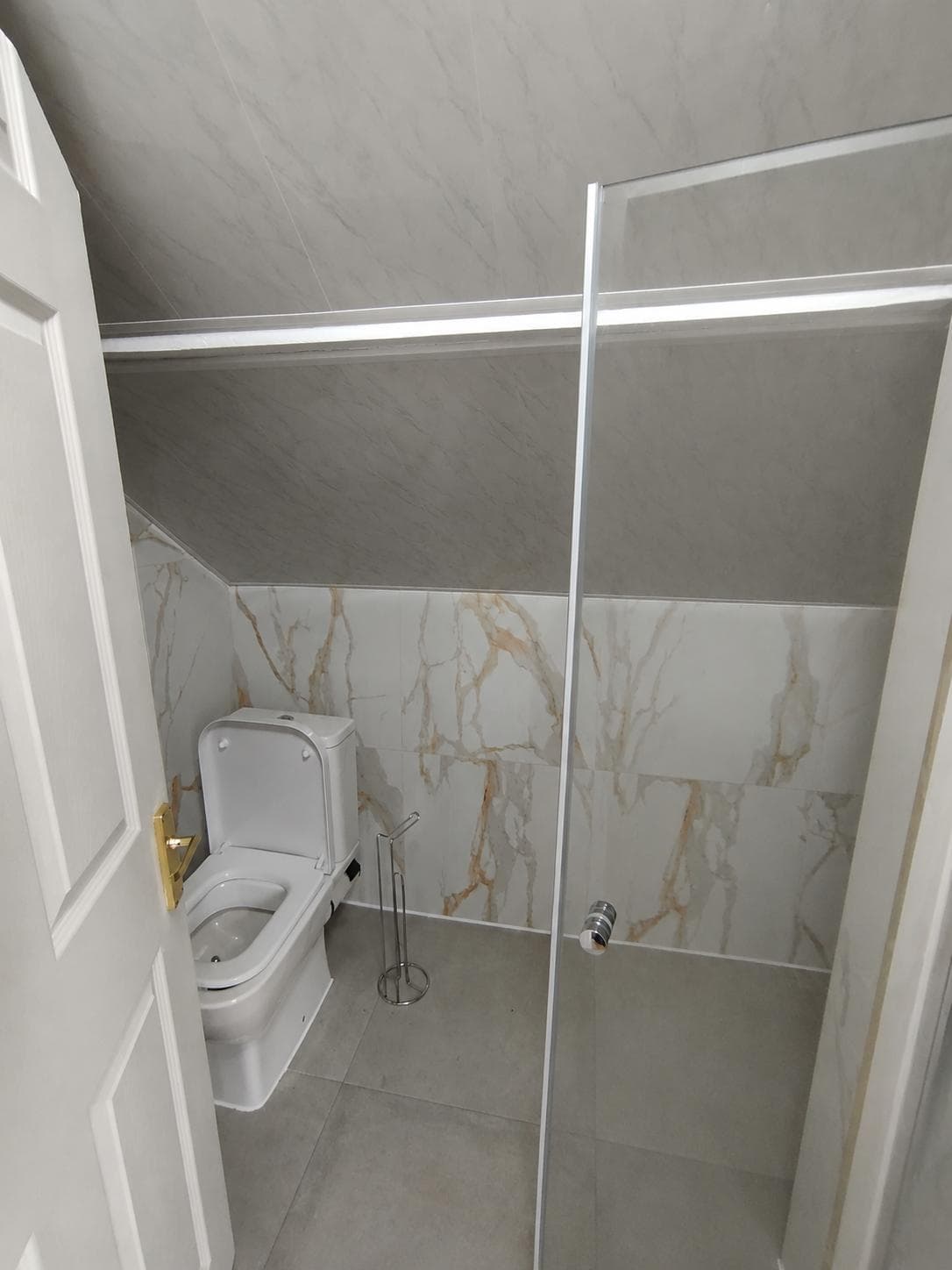 WC and frameless glass walk-in shower against calacatta marble walls