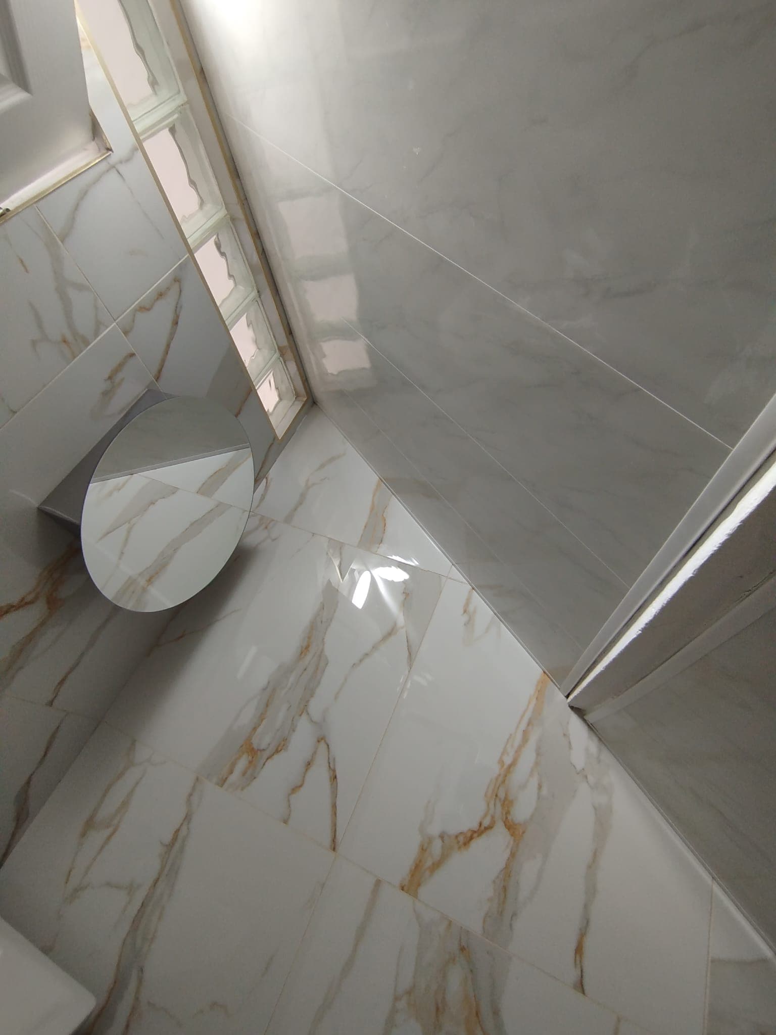 Detail of round mirror, vanity corner and marble floor tiling