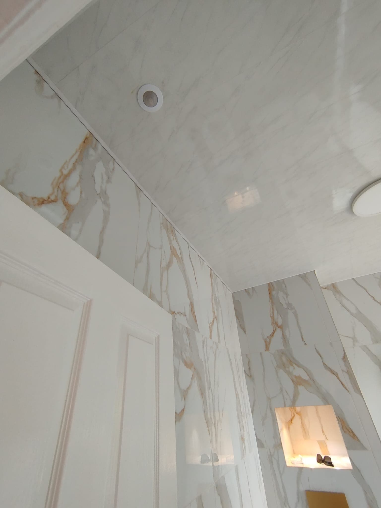 Close-up of calacatta marble wall tiles meeting the sloped ceiling