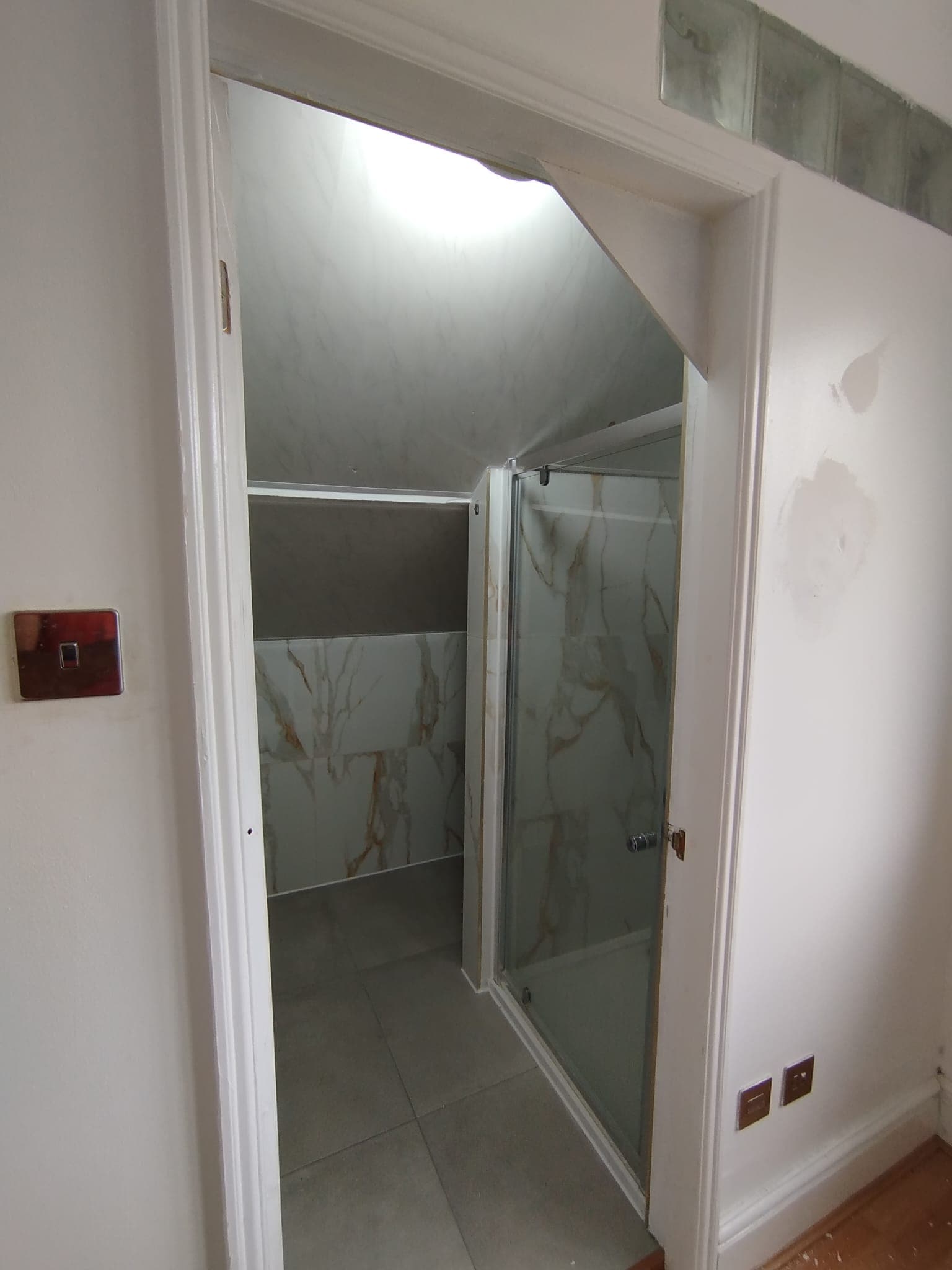 View into the bathroom from the hallway with shower enclosure beyond