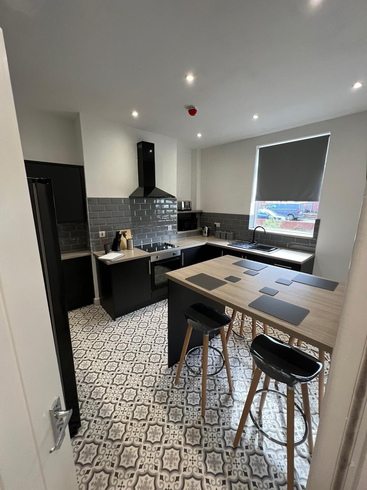 Communal kitchen with island, bar stools and patterned floor