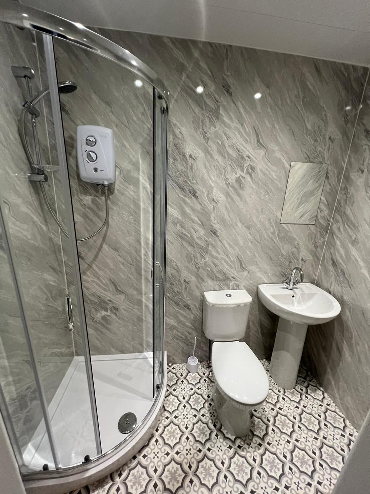 En-suite shower room with marble walls and patterned floor