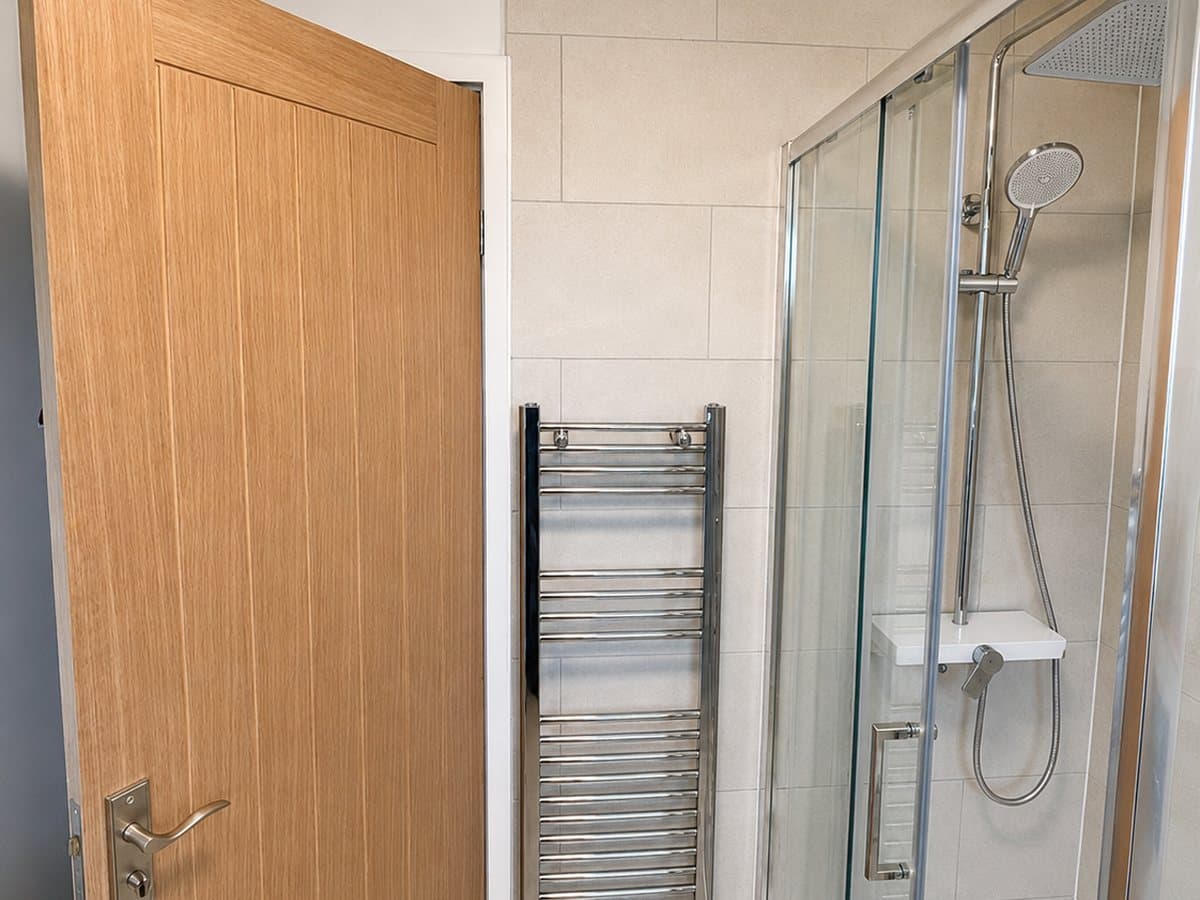 Walk-in shower enclosure with a solid oak door and chrome heated towel rail