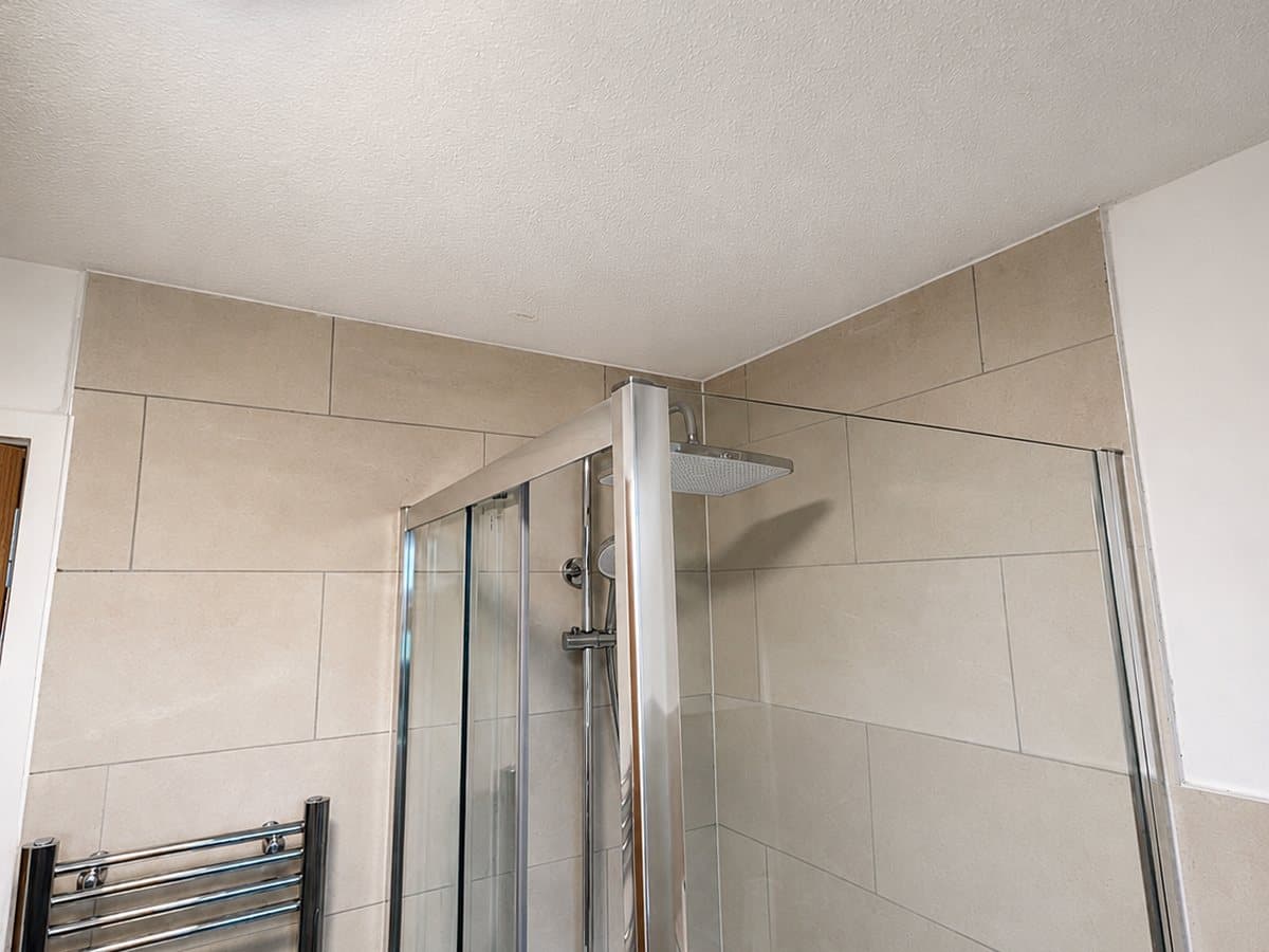 Shower enclosure with rainfall-style shower head and chrome heated towel rail