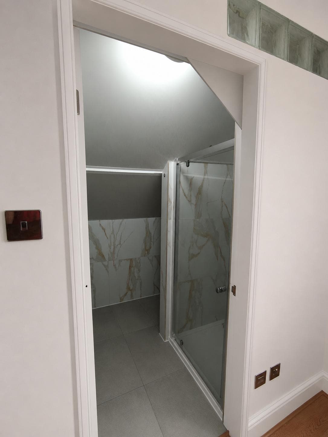 View into the bathroom from the hallway with shower enclosure beyond