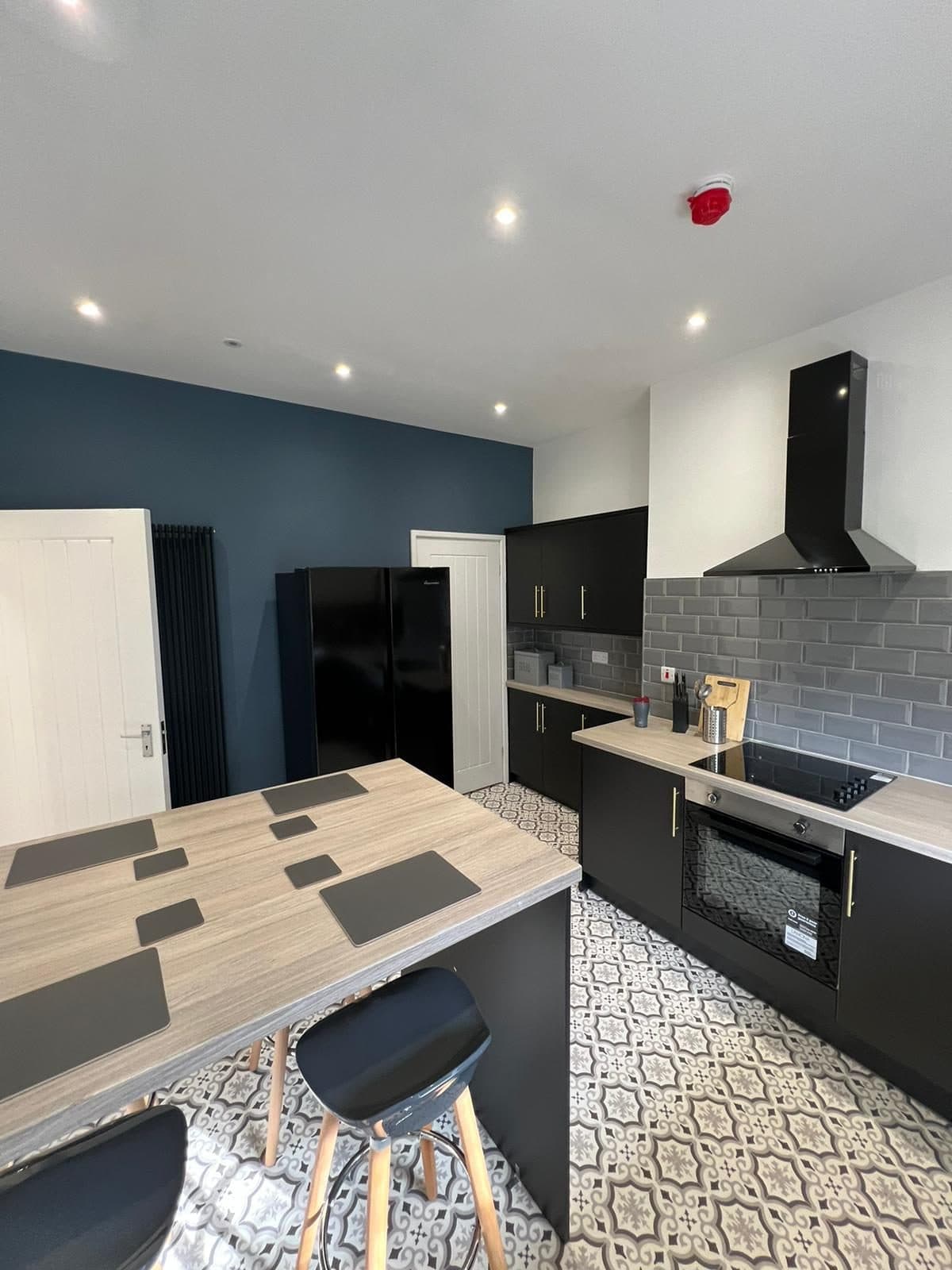 Modern shared kitchen with island and dark cabinetry after HMO conversion